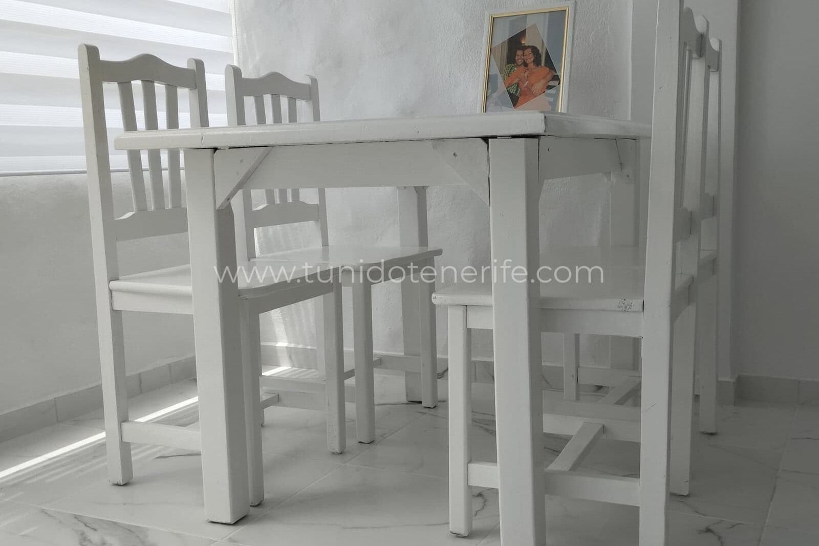 Masă albă cu patru scaune lângă fereastră