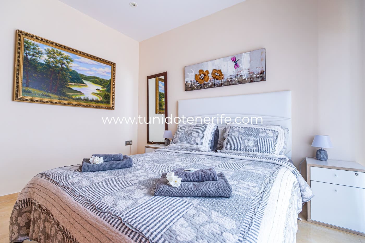 Chambre lumineuse avec lit double, tables de chevet et tableaux décoratifs