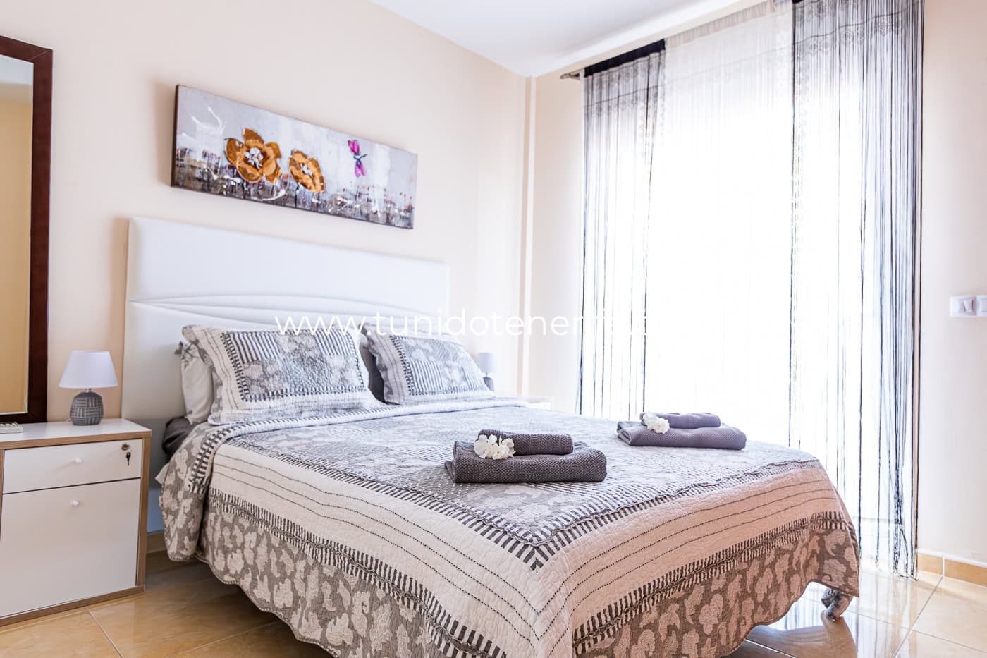 Chambre lumineuse avec lit double, tables de chevet et rideaux clairs