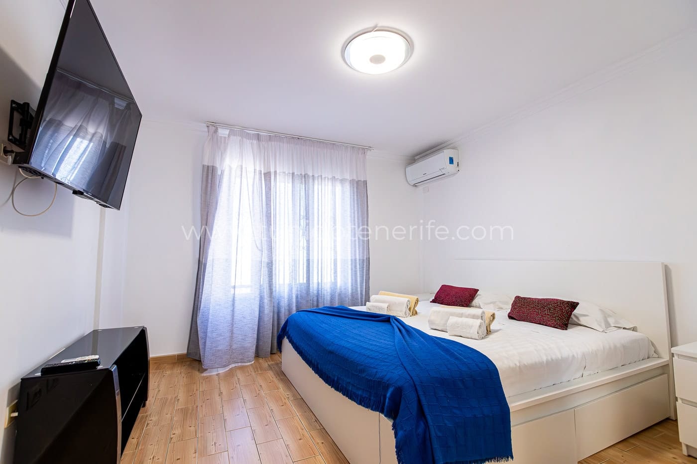 Camera da letto luminosa con letto matrimoniale, TV e tende