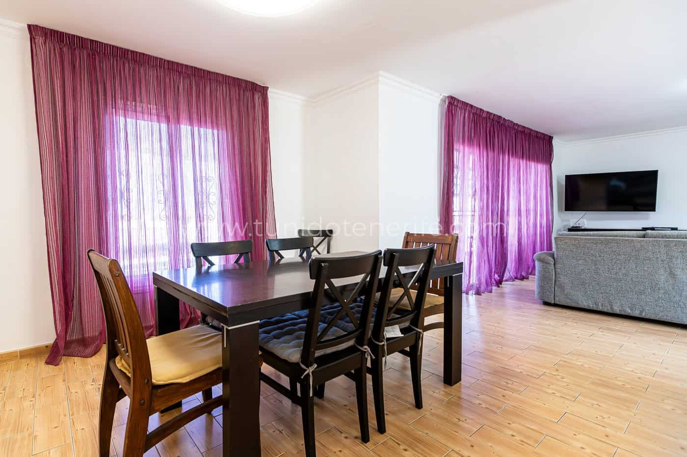 Sala da pranzo luminosa con tavolo in legno e tende viola