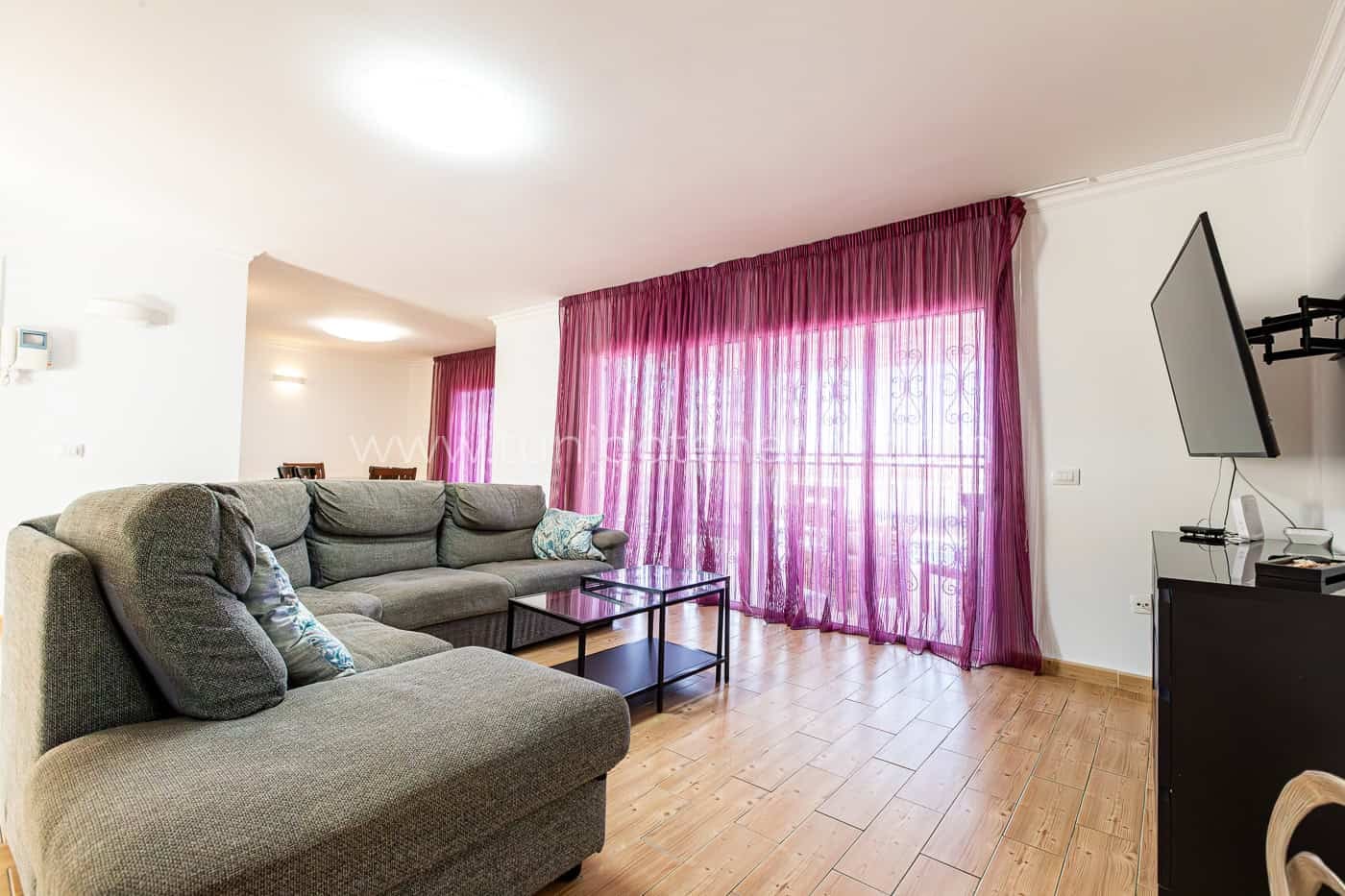Soggiorno luminoso con divano grigio e tende viola