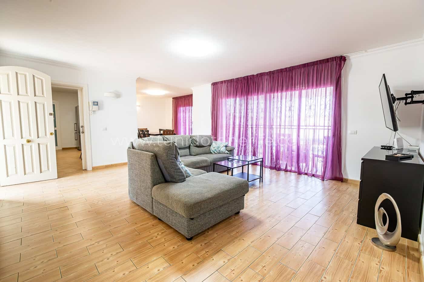 Soggiorno luminoso con divano grigio e tende viola