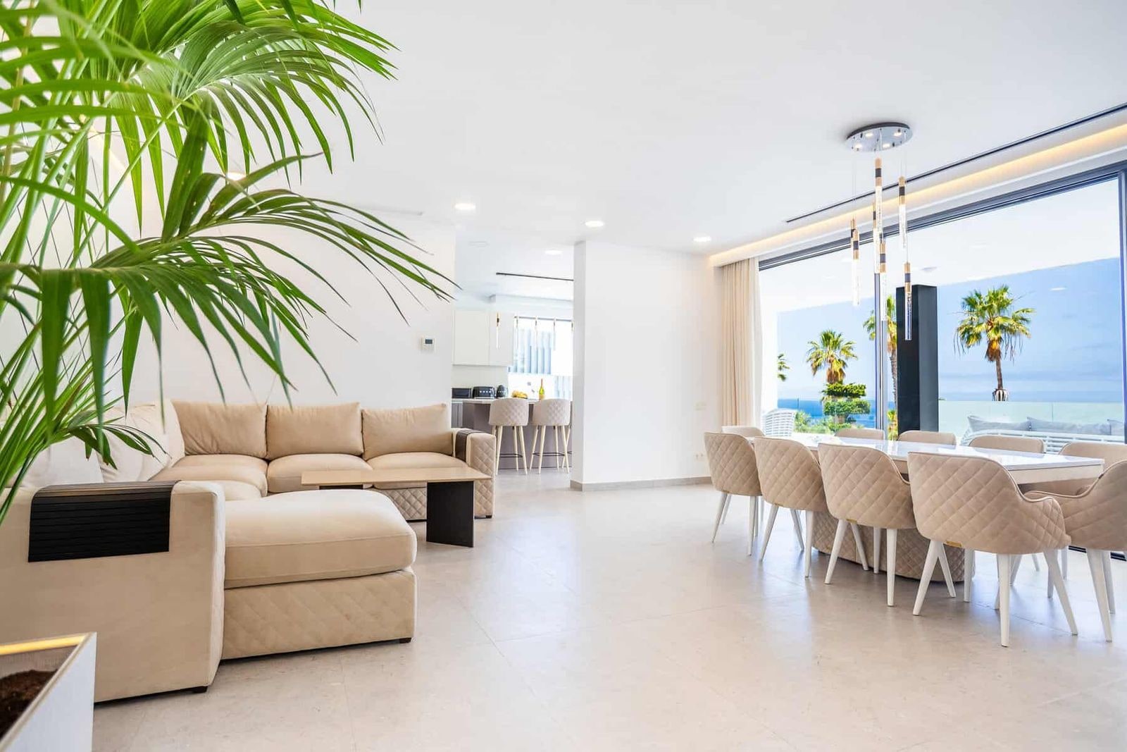 Salón luminoso con sofá beige y comedor junto a ventanales