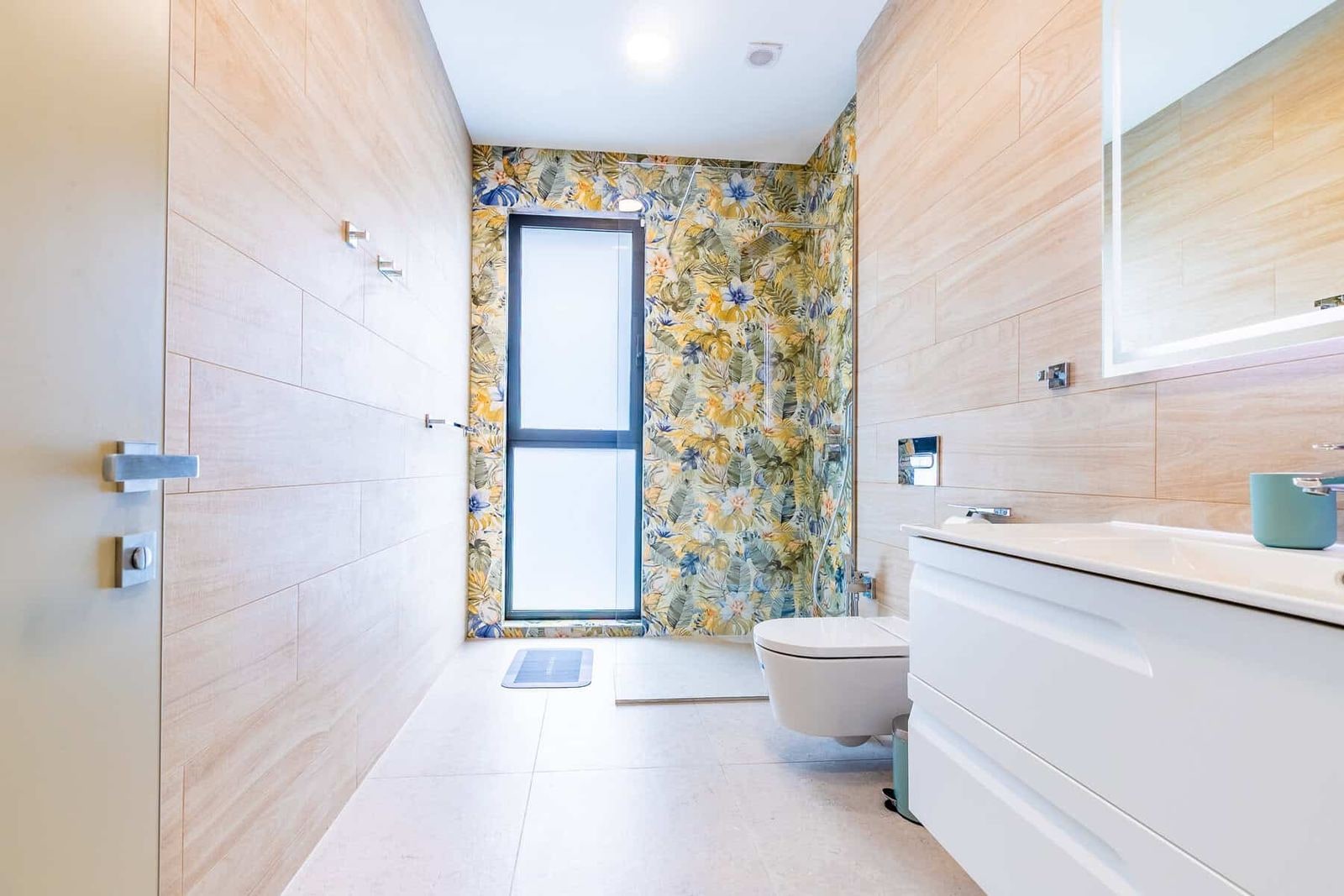 Baño moderno con papel pintado floral y ducha acristalada