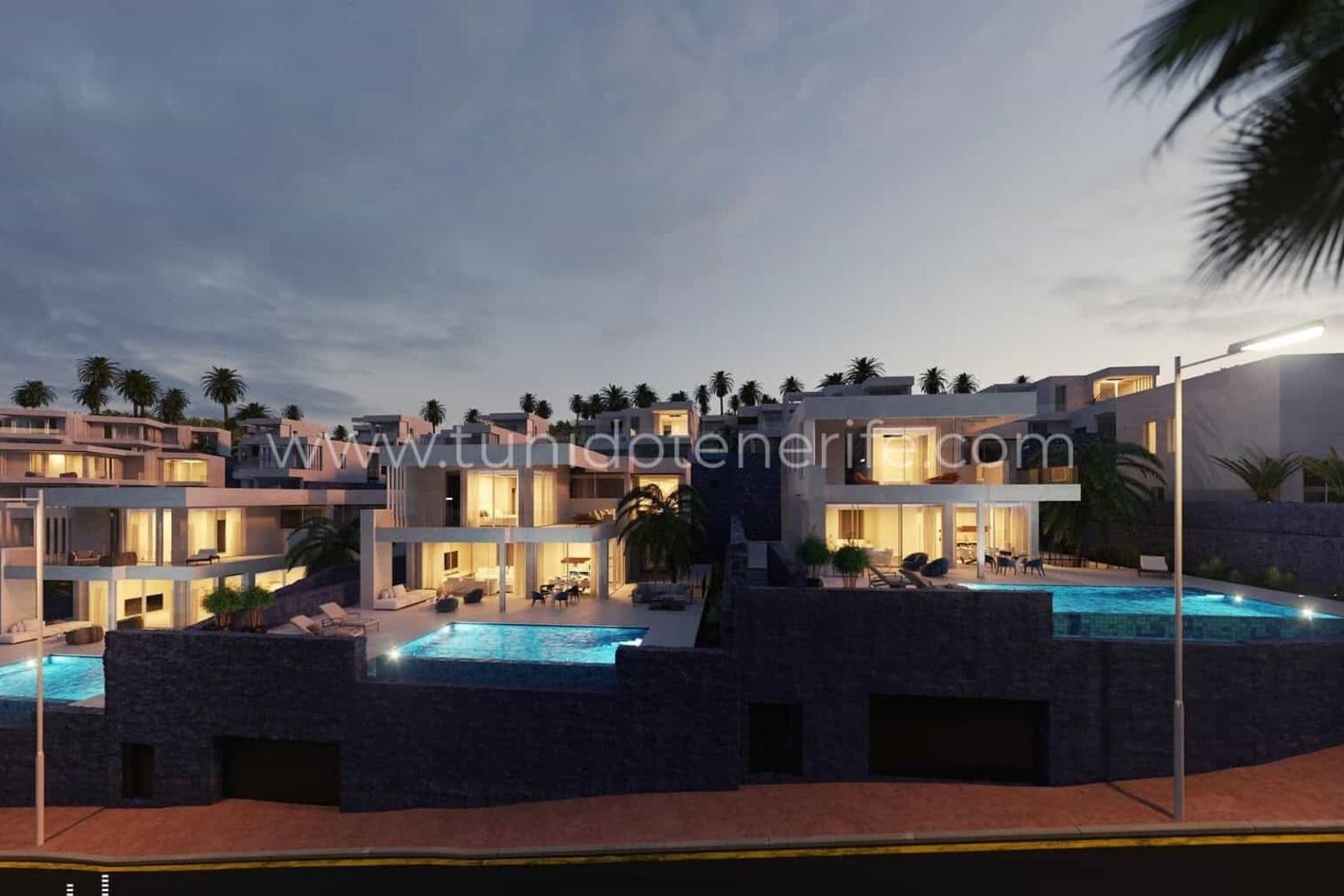 Lit swimming pool beside modern homes with terraces