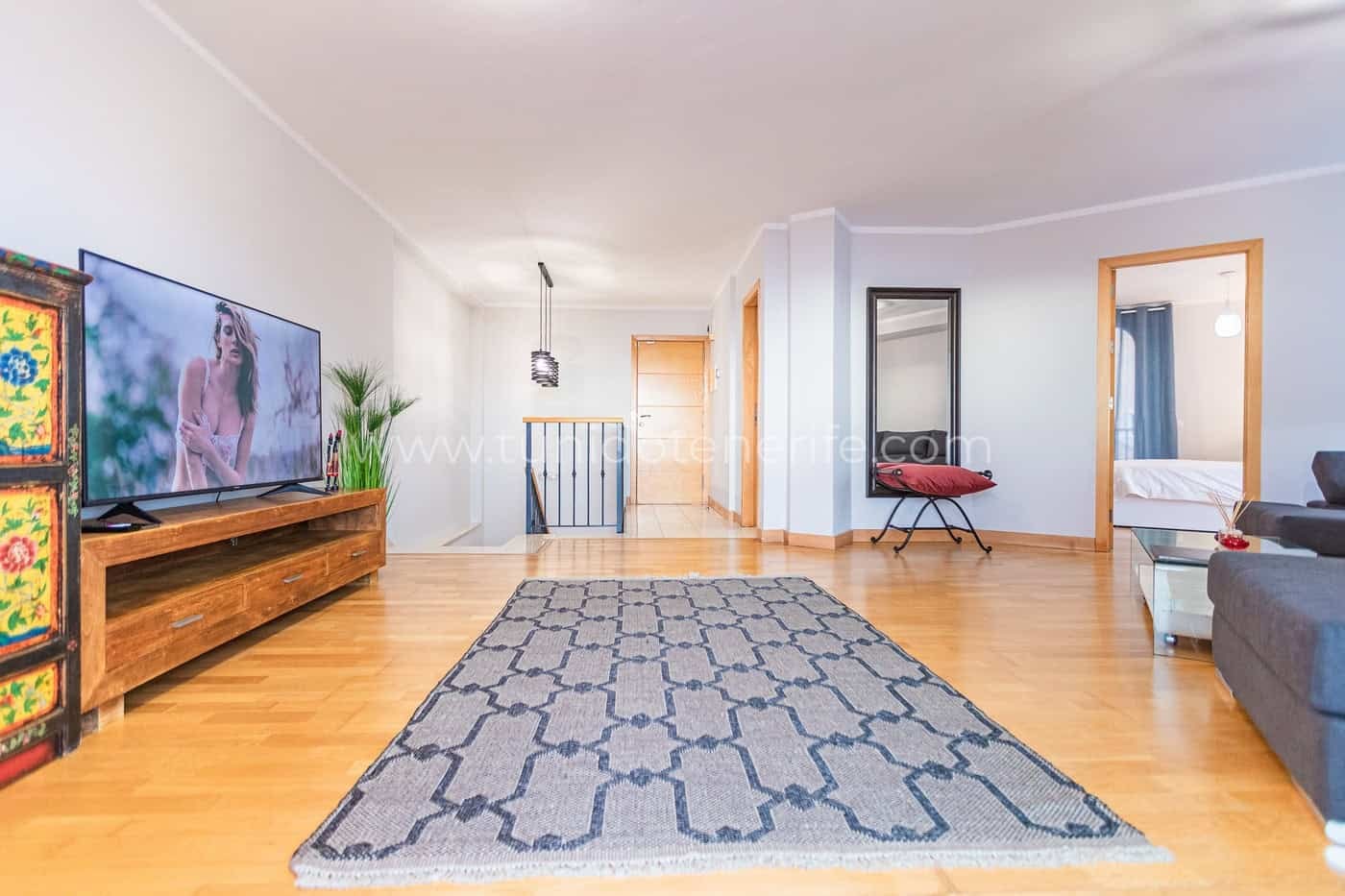 Salón amplio y luminoso con sofá, televisión y alfombra