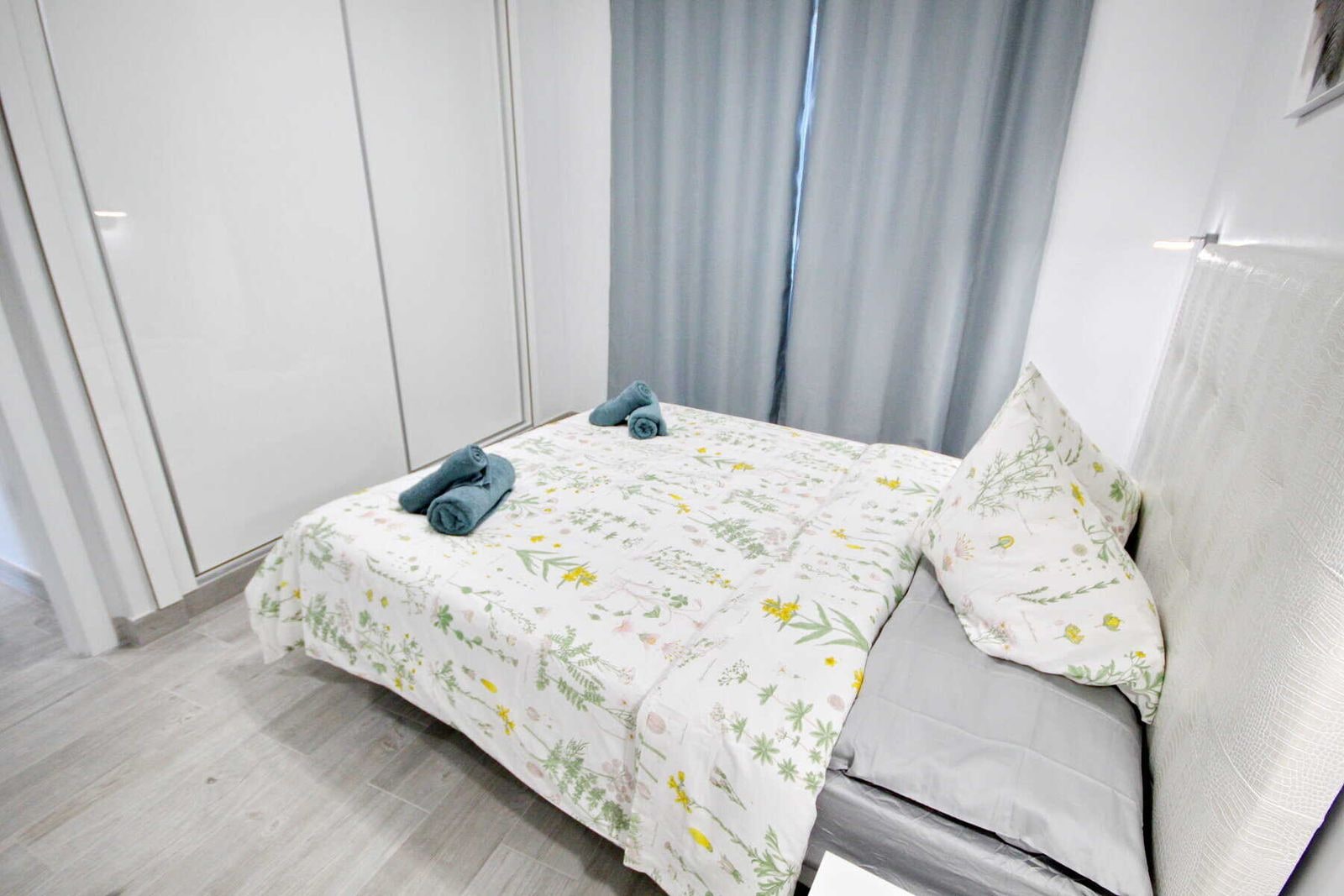 Camera da letto con letto matrimoniale, armadio bianco e tende grigie