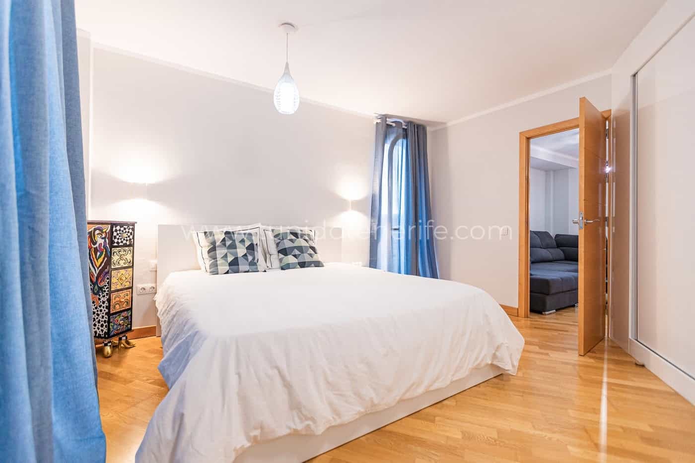 Dormitorio luminoso con cama doble, lámparas y suelo de madera