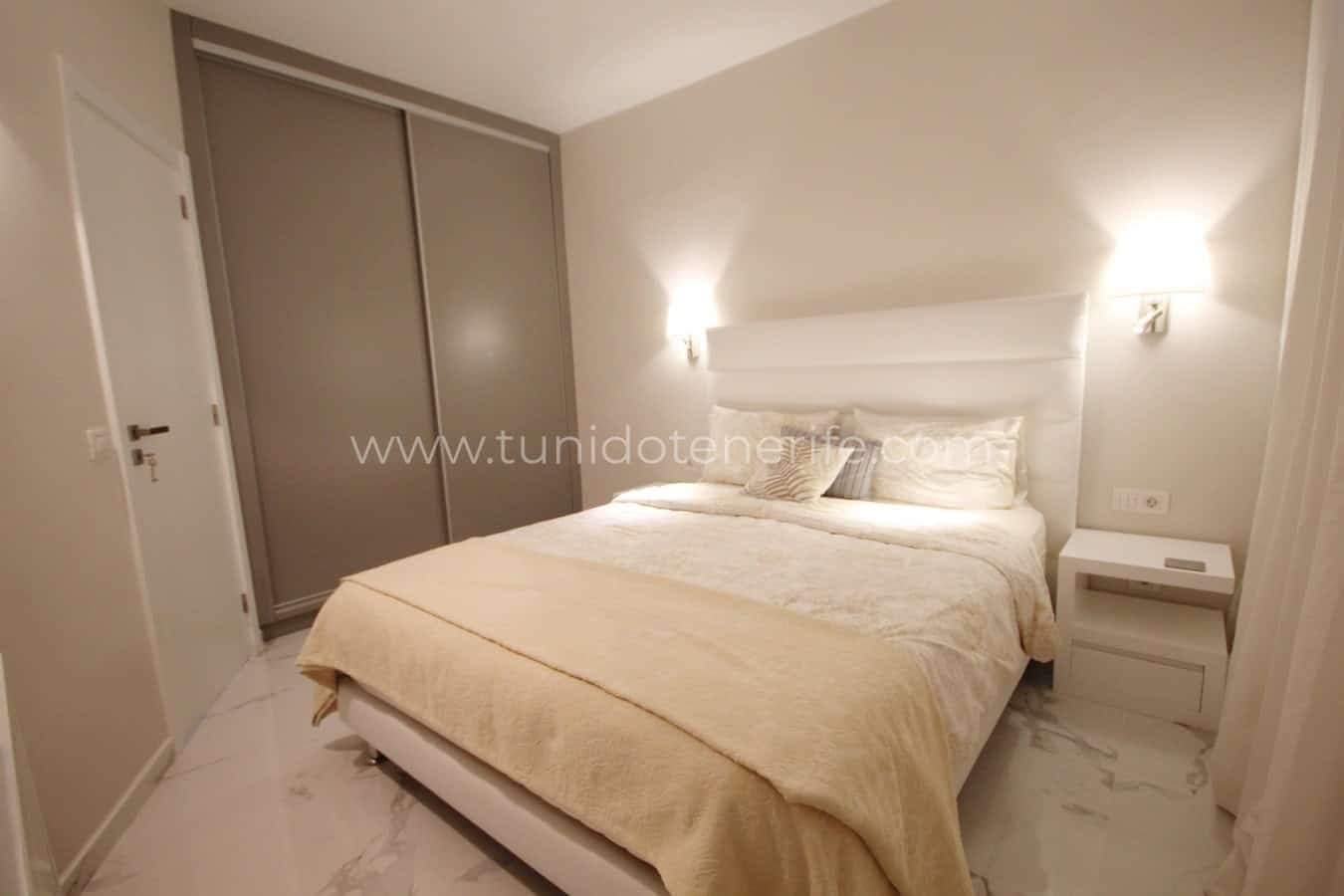 Bedroom with double bed, built-in wardrobe and white bedside tables
