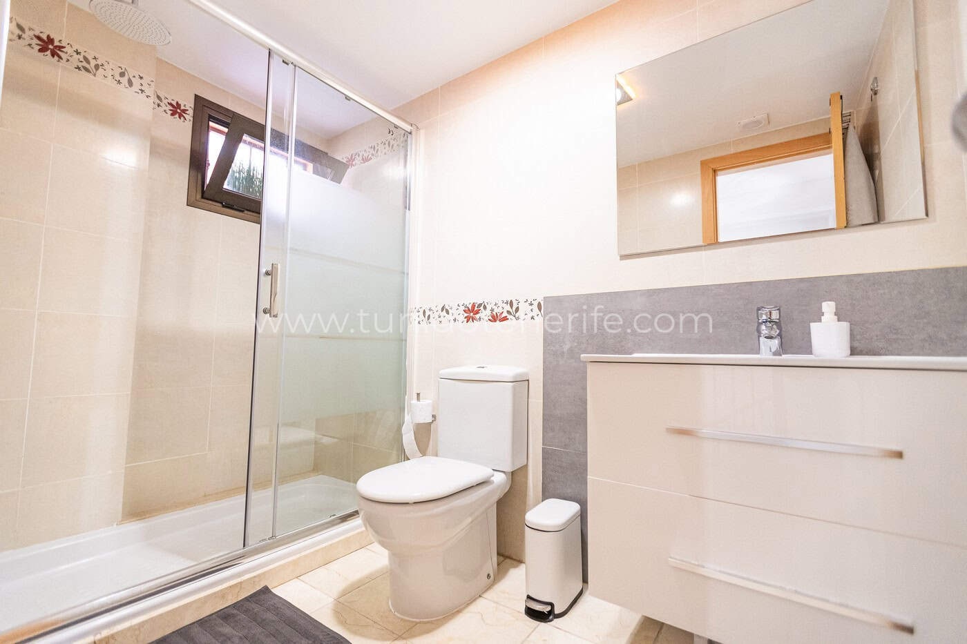 Baño con ducha de cristal, lavabo y espejo