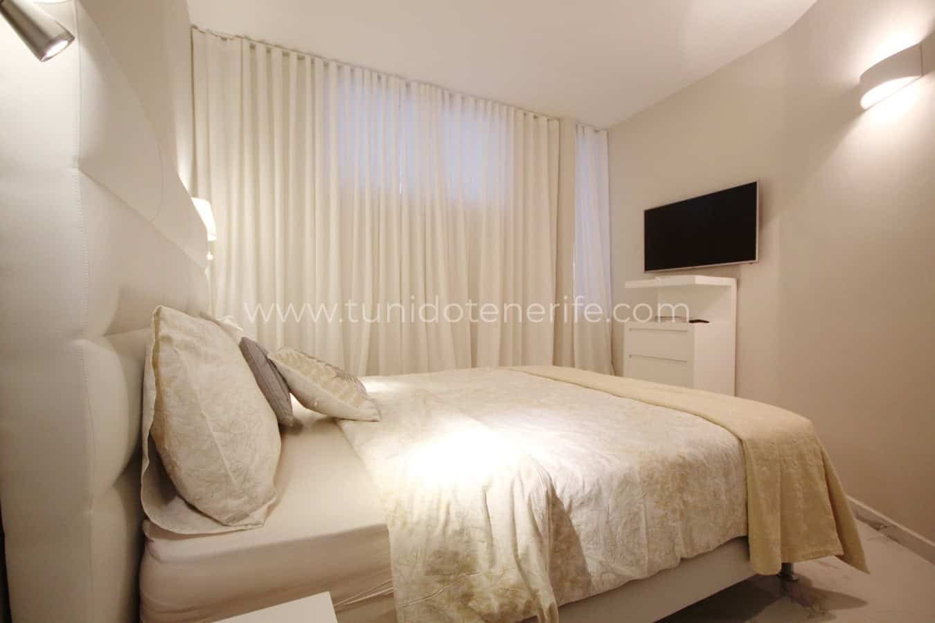 Bright bedroom with made bed and white curtains
