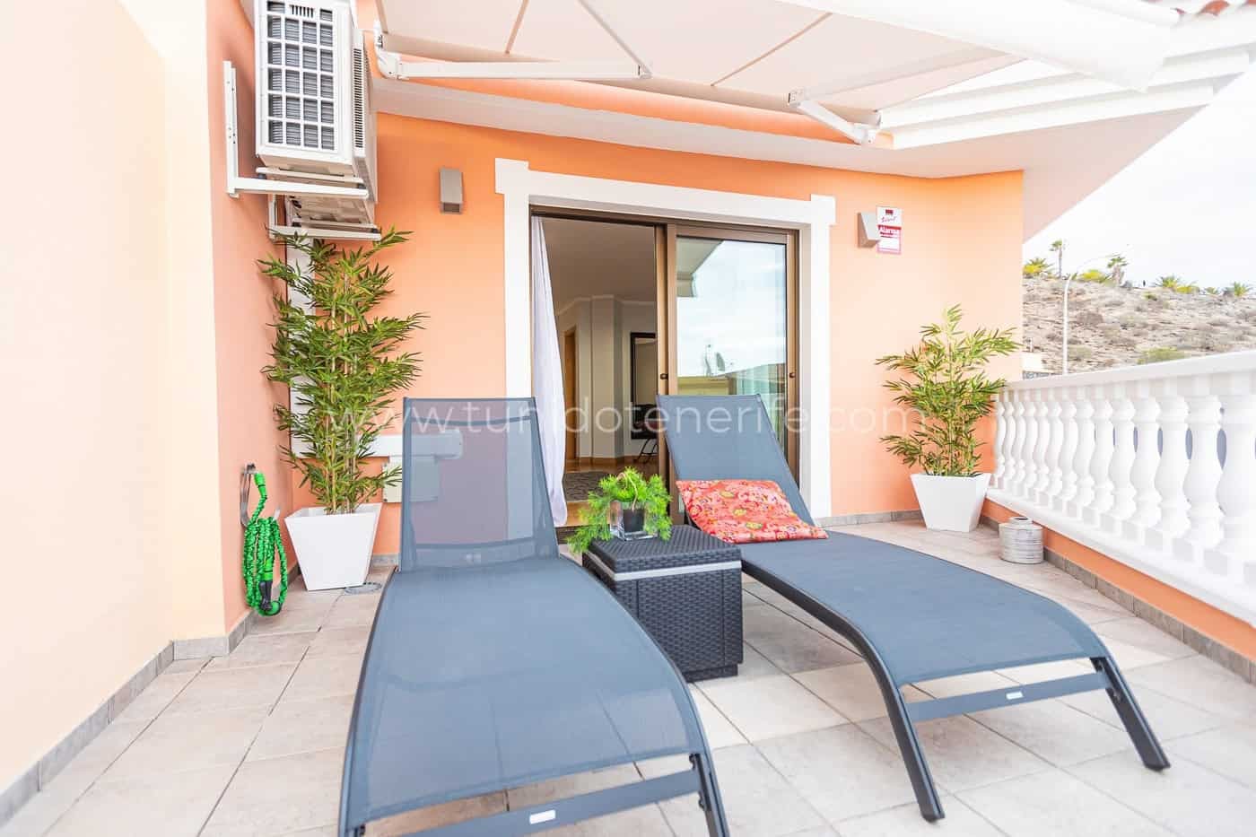 Terraza con tumbonas, mesa auxiliar y plantas en macetas