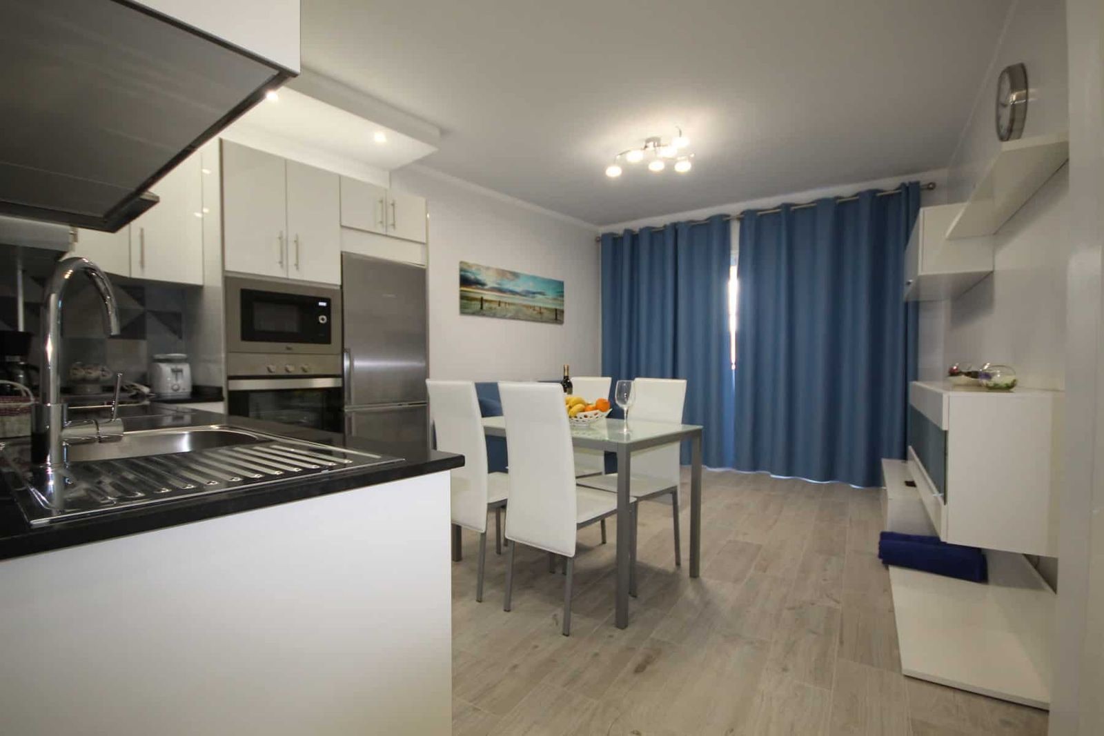 Cucina open space con zona pranzo e tende blu