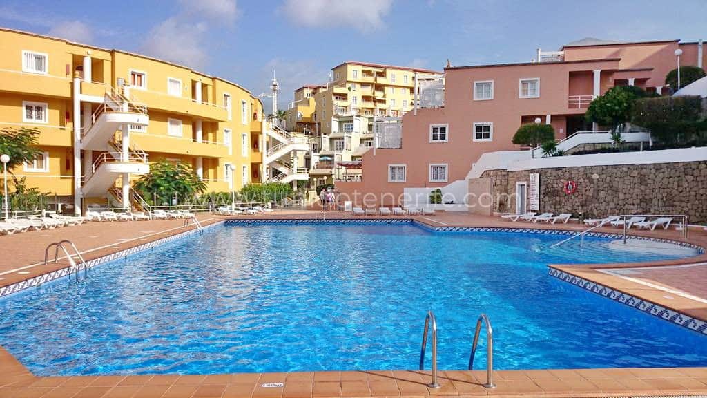 Piscina esterna condominiale con acqua blu e edifici intorno