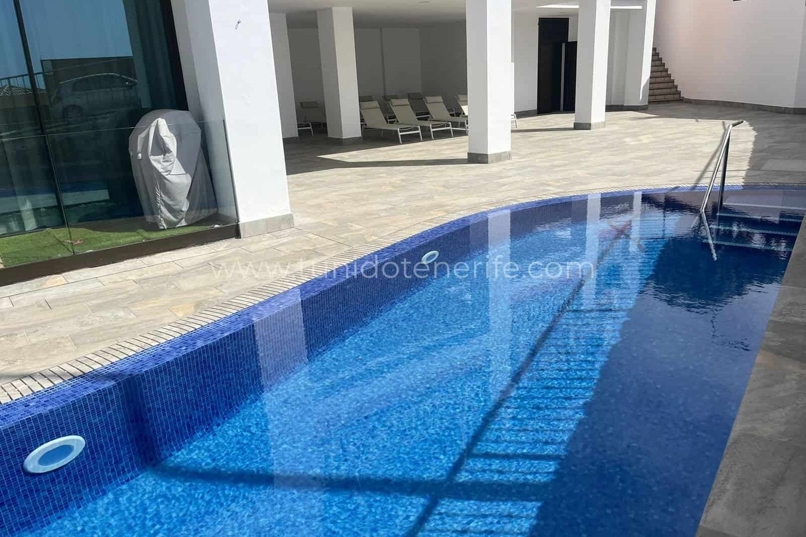 Piscina exterior junto a terraza pavimentada