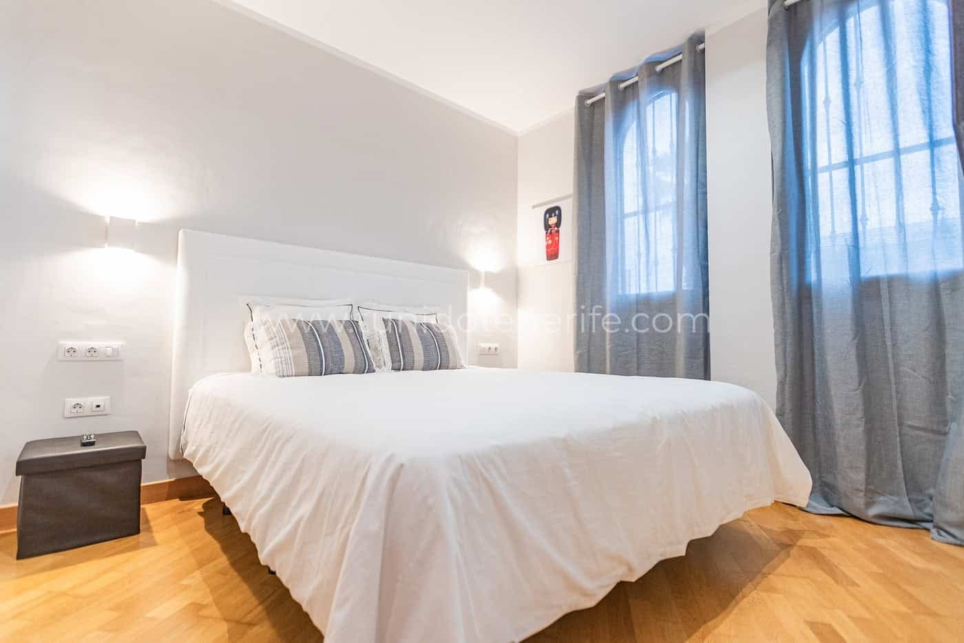 Dormitorio luminoso con cama doble y cortinas grises