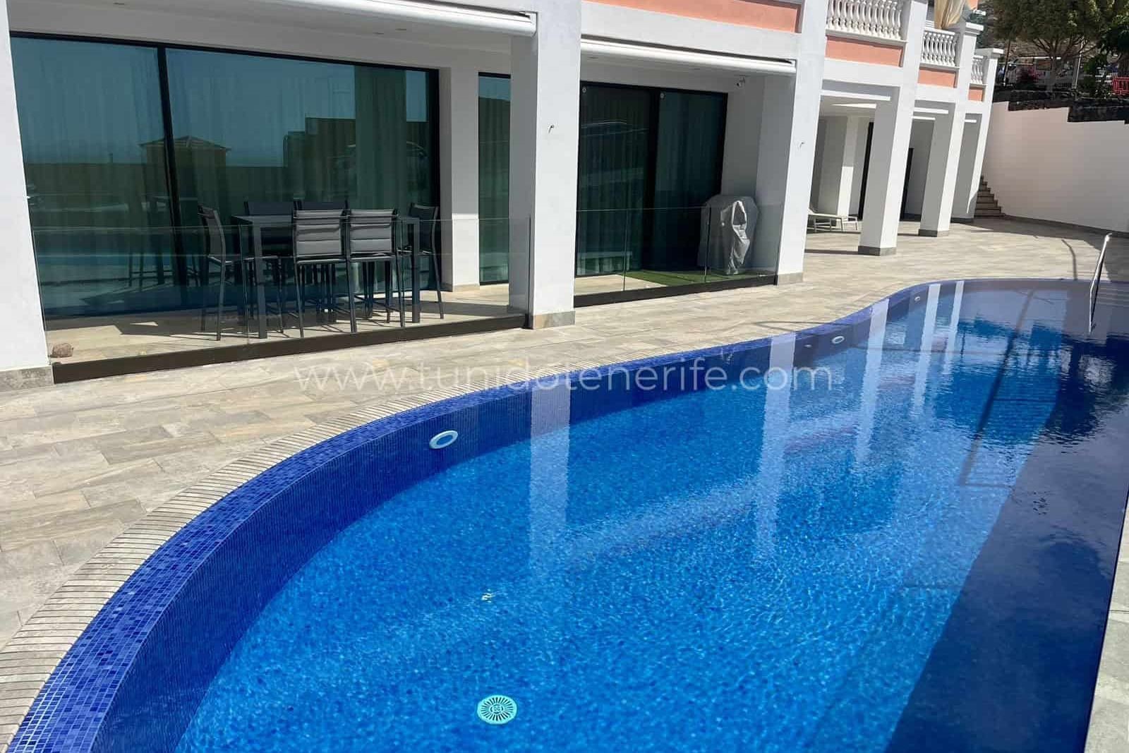 Piscina exterior junto a grandes puertas correderas de cristal