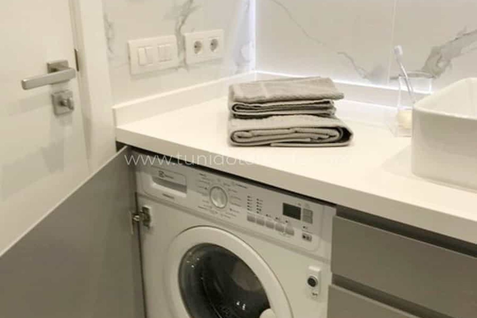 Modern laundry room with integrated washing machine and white countertop
