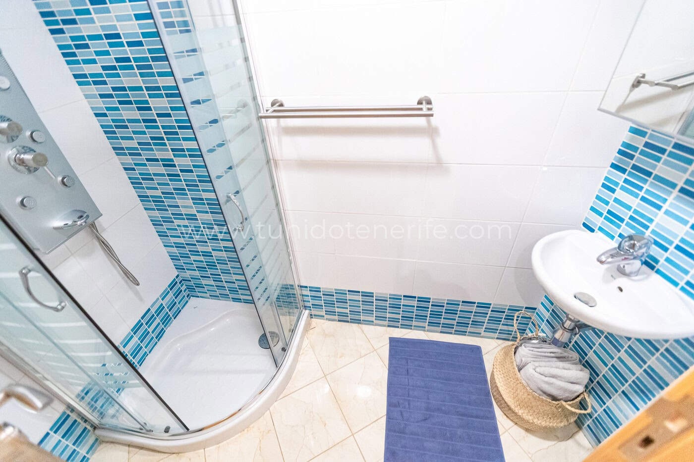 Baño con ducha de cristal, lavabo y azulejos azules