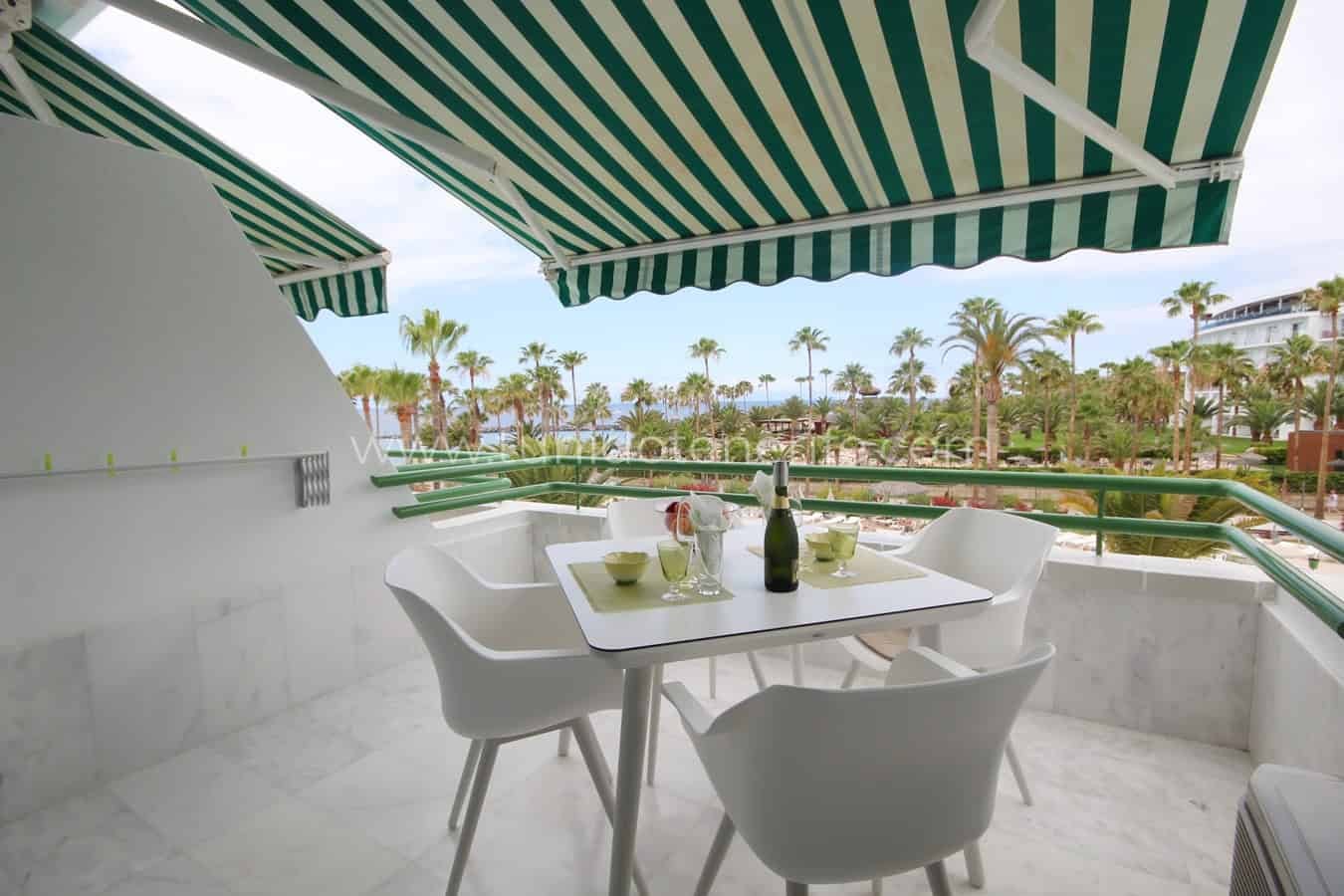 Terrace with table, chairs and green striped awning