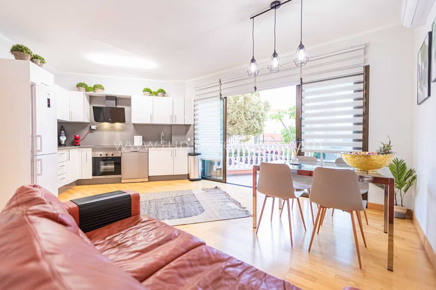 Salón con cocina abierta, mesa de comedor y salida a terraza