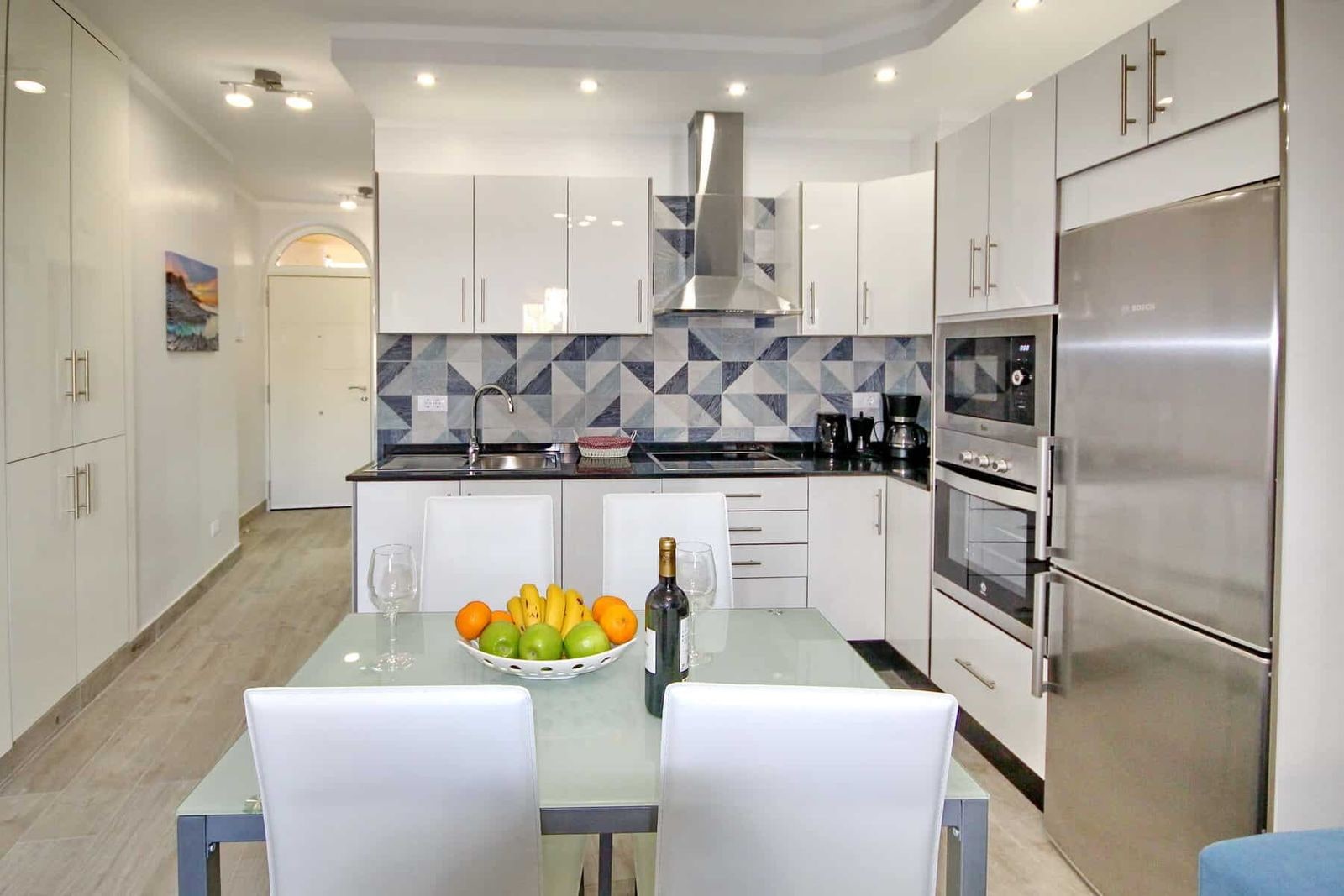 Cucina moderna bianca con tavolo in vetro ed elettrodomestici integrati