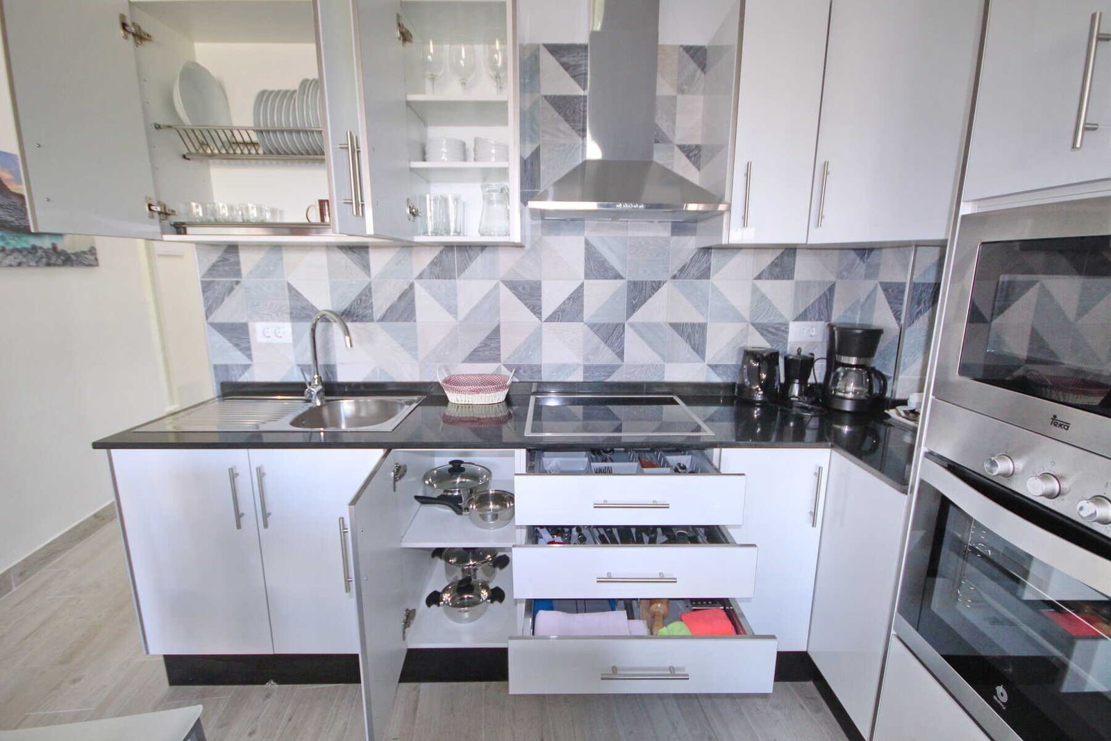 Cucina moderna con mobili bianchi e piastrelle geometriche