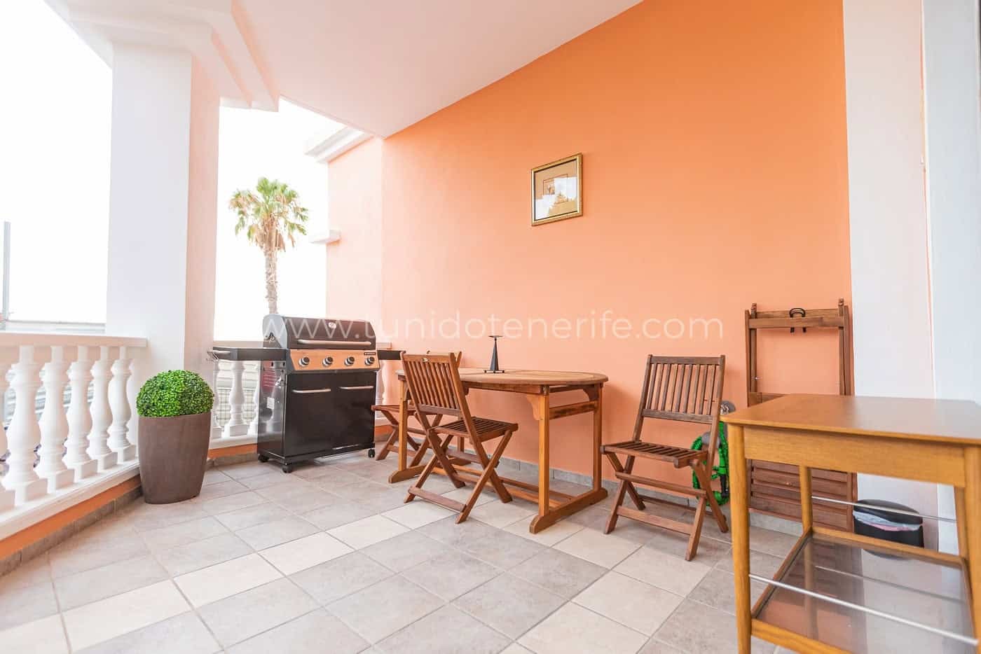 Terraza cubierta con mesa, sillas y barbacoa
