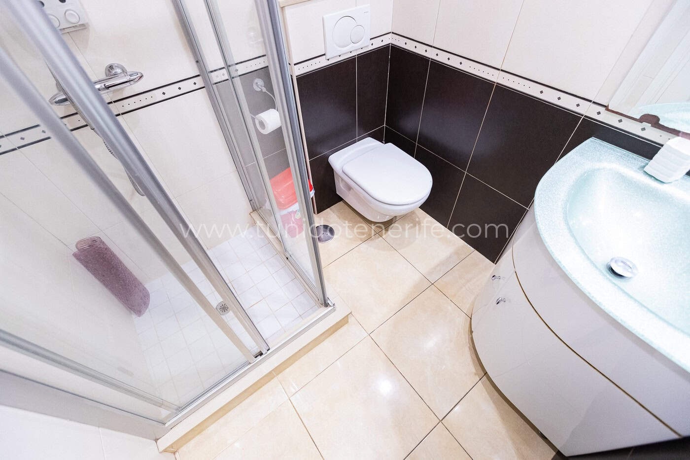 Salle de bain avec douche vitrée, toilettes et lavabo
