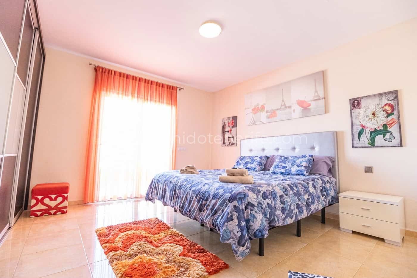 Chambre lumineuse avec lit double, tables de chevet et rideaux orange