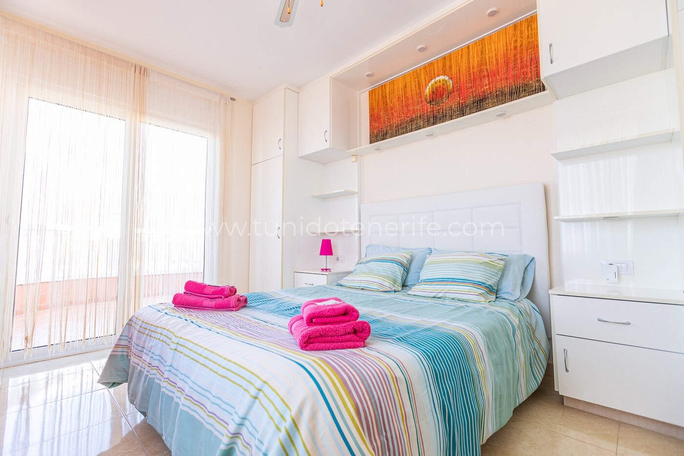 Chambre lumineuse avec lit double, armoires blanches et rideaux clairs