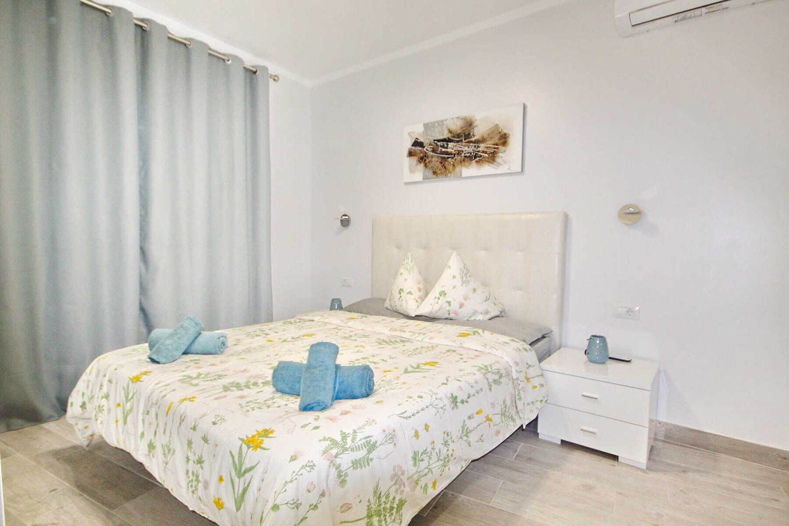 Camera da letto luminosa con letto matrimoniale, comodini e tende grigie