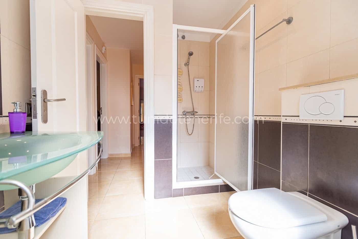Salle de bains avec douche, lavabo en verre et toilettes