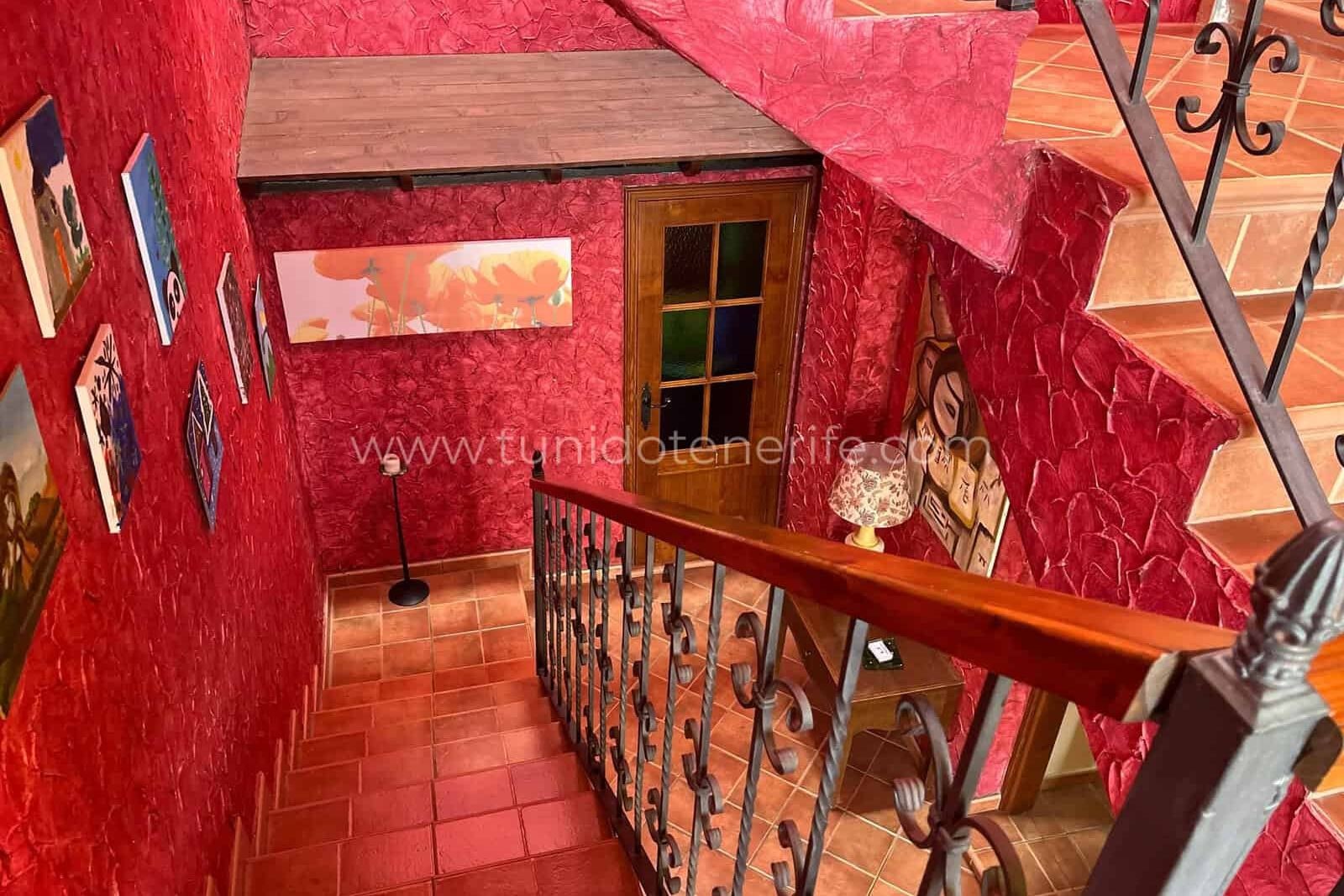 Interior staircase with red walls and wrought-iron railing