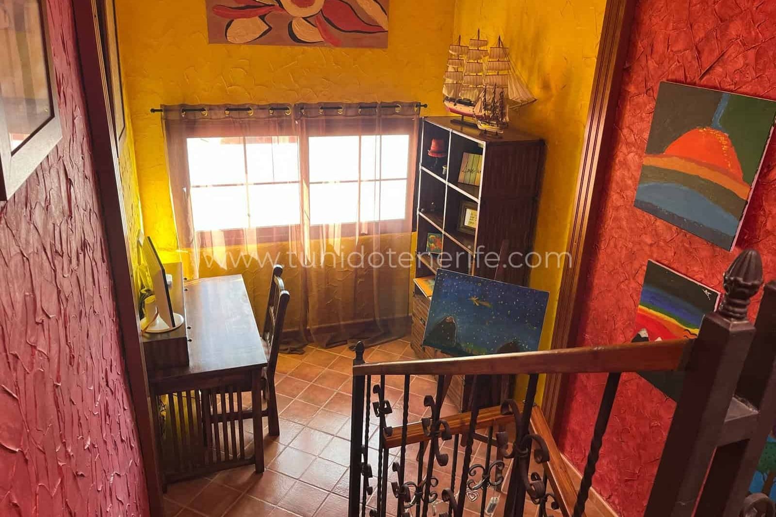 Staircase with red wall and small table by the window