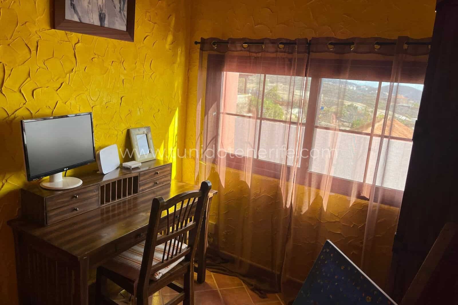 Wooden desk with chair beside large windows with curtains