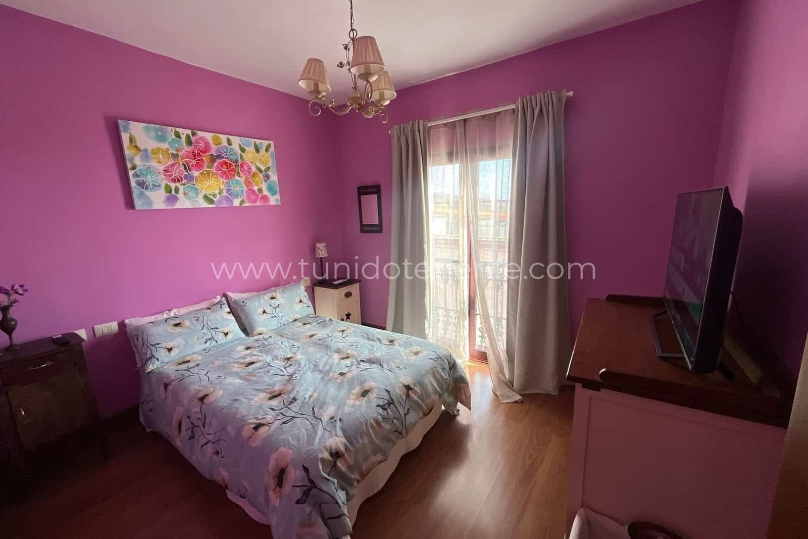 Bedroom with purple walls, double bed and television