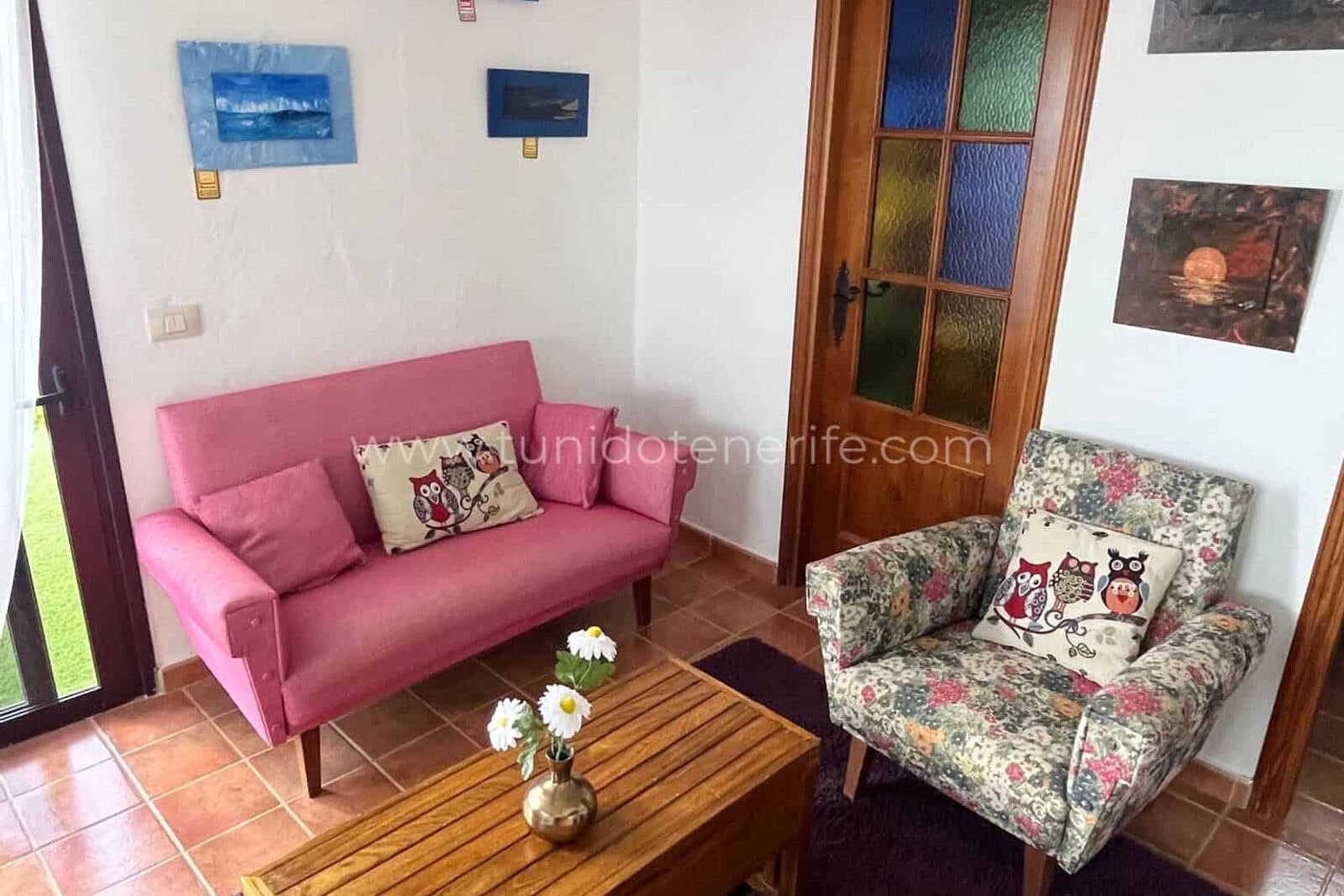 Living room with pink sofa, patterned armchair and wooden table