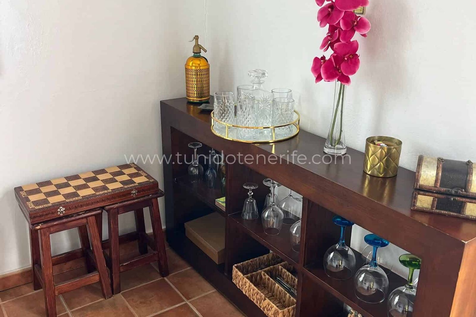 Sideboard with glasses, stools and pink orchid