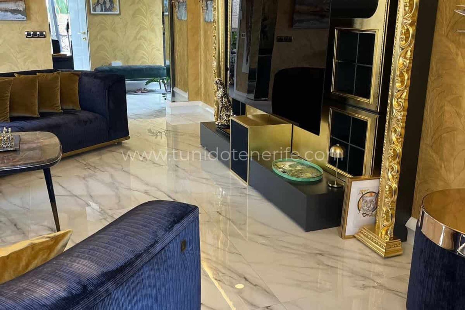 Salón elegante con sofá azul, chimenea y televisor grande