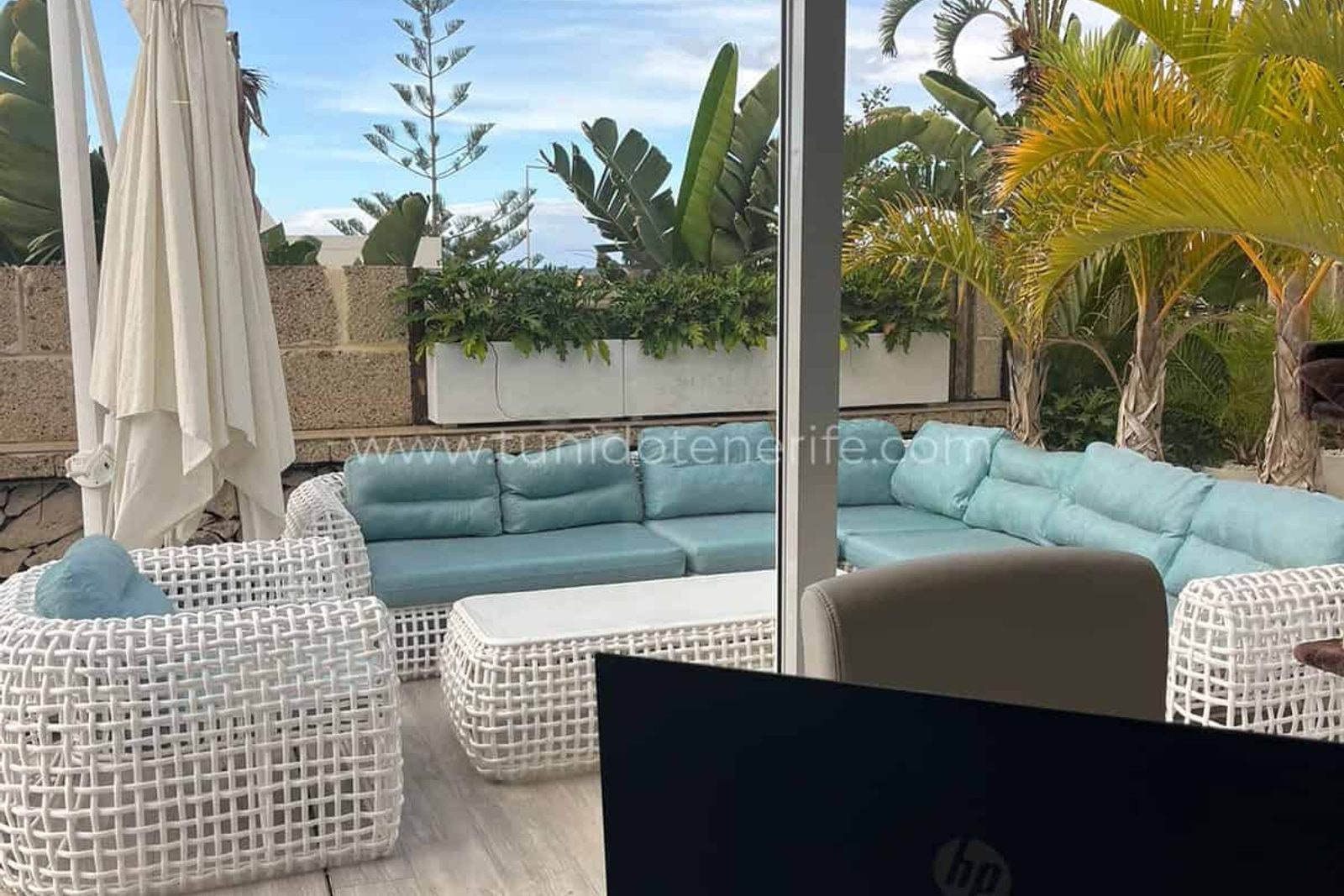 Terraza con sofás de exterior y sombrilla blanca