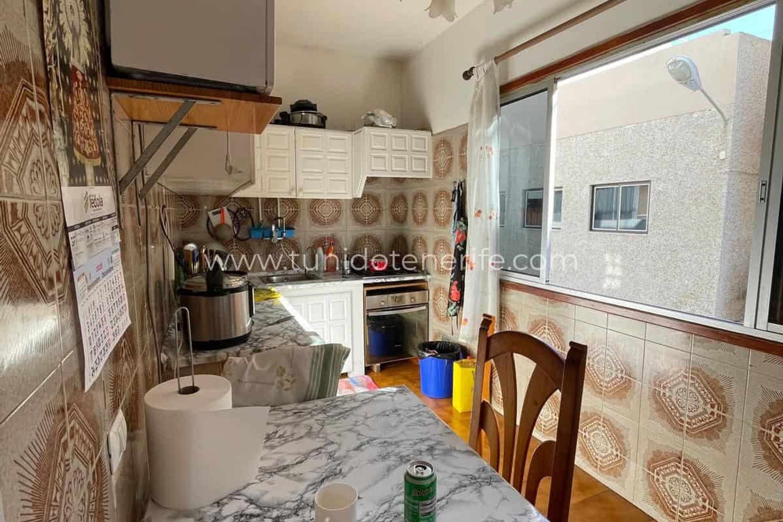 Small kitchen with table, white cabinets and large window