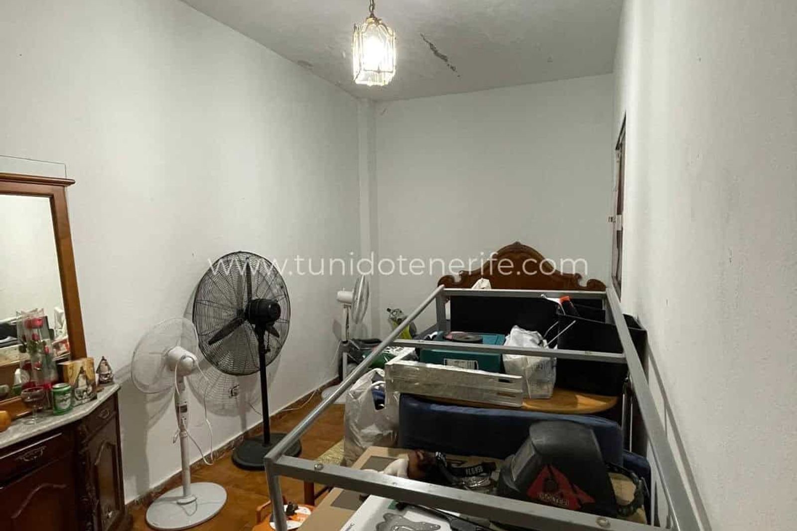 Bedroom with bed, standing fan and dresser