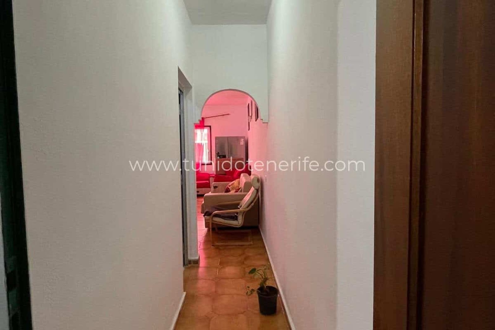 Narrow hallway with tiled floor and archway at the end