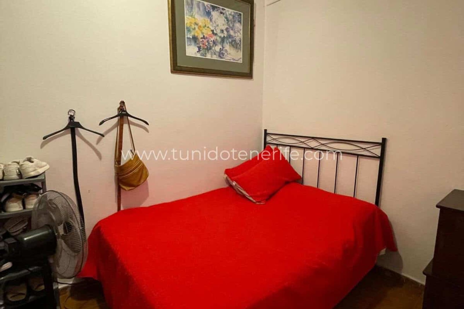 Bedroom with red single bed and wall painting