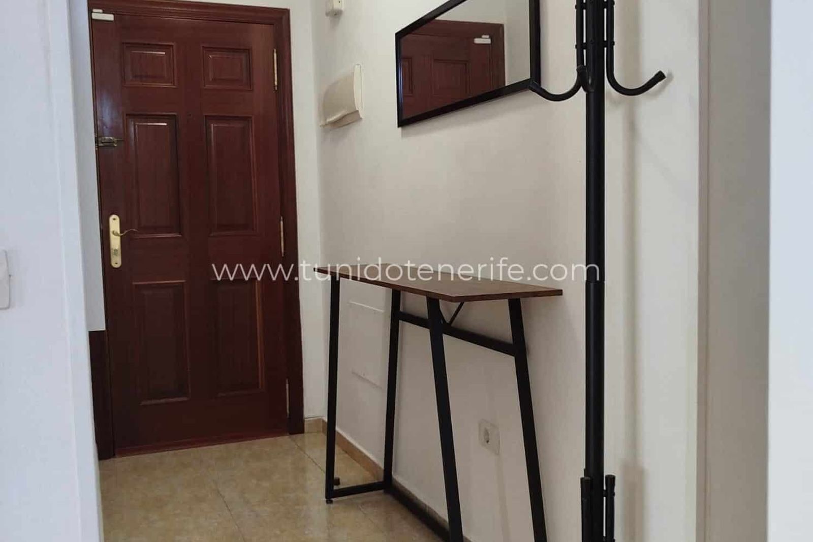 Recibidor estrecho con puerta de madera y espejo de pared