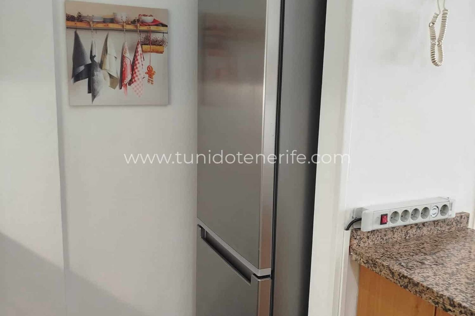 Cocina con frigorífico, encimera de granito y perchero de pared