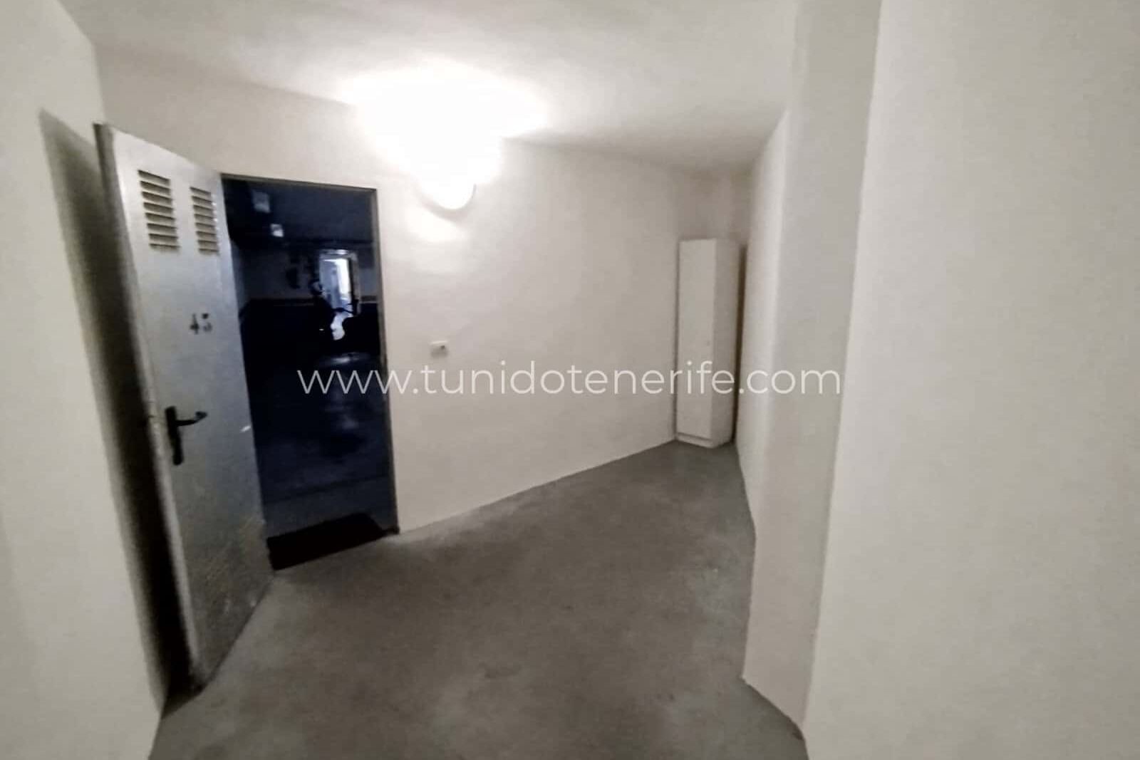 Pasillo interior estrecho con puerta metálica y pared blanca