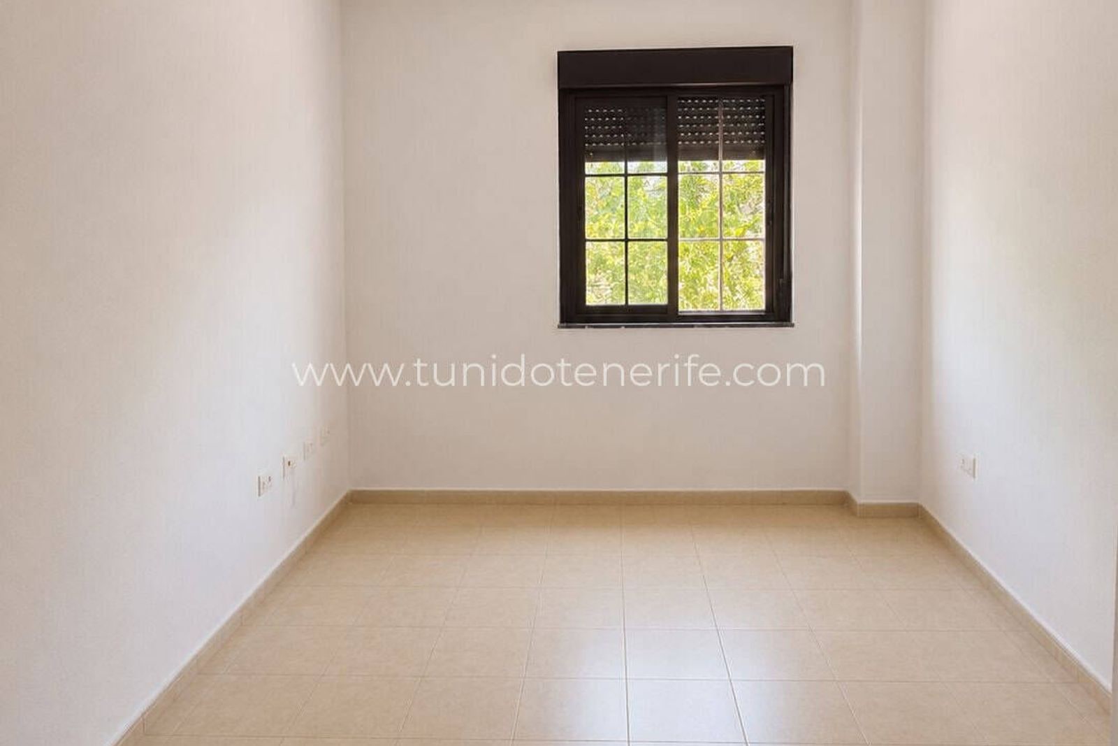 Habitación vacía con ventana y suelo de baldosas